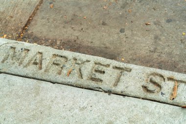 Curb that has Market Street engraved in silicon valley san jose california with black asphalt and gray cement. Late afternoon shade in downtown urban or suburban areas of the neighborhood.