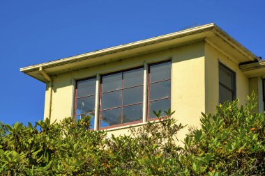 Görünür oda ya da daire düz çatılı ve ön ya da arka bahçesi ağaçlı ve mavi silueti olan sarı çimento kaplamalı. Amerikan banliyösünde görünür penceresi olan mahallede boşluk kopyala.