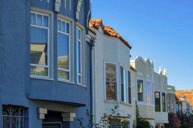 Öğle vakti güneş gören gölgeli evler. Mavi beyaz cepheli, görünür pencereli ve kırmızı kiremitli. Mahallede ya da şehir merkezinde, orta sınıf kasaba bölgelerinde..