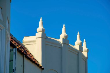 Beyaz boyalı ve sivri kuleli modern Amerikan üst sınıf banliyö bölgesinde dekoratif ev ya da ev cephesi. Kırmızı kiremitleri olan ve mavi gökyüzünü kopyalayan bir bina..