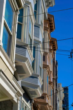 San Francisco California 'nın tarihi bölgelerinin yoğun kentsel alanlarındaki dekoratif evler ya da ev cepheleri. Elektrik hatları ve Amerikan mahallelerinde mavi gökyüzü geçmişi olan şehir merkezi..
