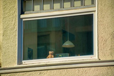 Küçük çocuk oyuncağı ve lamba şehir merkezinin dış duvarında bej kaplama duvar ile banliyö penceresinden görülüyor. Orta sınıf bölgesinde öğleden sonra güneşli bir ev ya da apartman kompleksi.