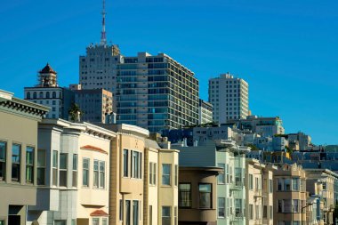 Şehir merkezindeki gökdelen binaları San Francisco California 'nın tarihi bölgelerinde sıra sıra evler ya da evler. Öğleden sonra güneşinde şehrin kentsel mahallelerinde gökyüzü mavidir..