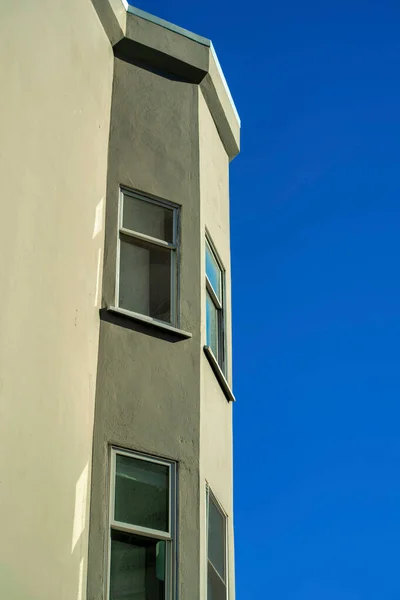 ベージュまたは茶色のスタッコビル近代的な街のダウンタウンの都市や郊外の地区に外装セメントビル 暗いアクセントフレームと青いコピースペースの空を持つ可視窓 — ストック写真