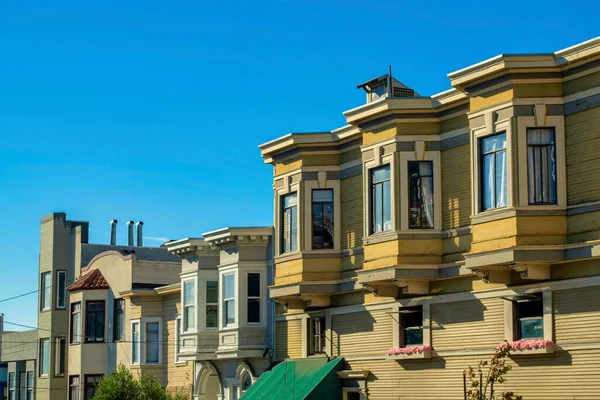San Francisco 'nun tarihi bölgelerindeki dekoratif evler. Gün ortası güneşinde mavi gökyüzü. Modern şehir merkezinde bej ve beyaz renkli dış görünüş ve dış görünüş.