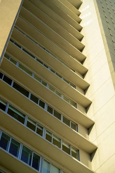 stock image Low view of hotel or residential and commercial real estate building with decorative facade walkways and interior walls. Visible sun streaks on side of buiilding in industrial or urban area of neighborhood.