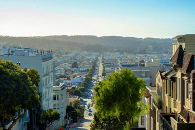 San Francisco 'nun merkezindeki tarihi bölgelerdeki tepenin tepesinden, şehrin orta sınıf mahallelerine bakın. Binalar ve evler, beyaz ve mavi gökyüzü dağları, güneş ve gölge..