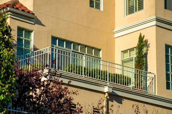 Decorative balcony with white hand rails and beige stucco cement building on house or home in neighborhood downtown. Commercial and residential real estate in american dream suburbs.