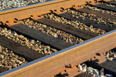 Metal kirişli tren rayları ve ahşap kereste levhaları ya da çakıllı zeminde paslı güneş ışığı. Kırsal ve endüstriyel alanlarda taşımacılık için kullanılan şehirde.