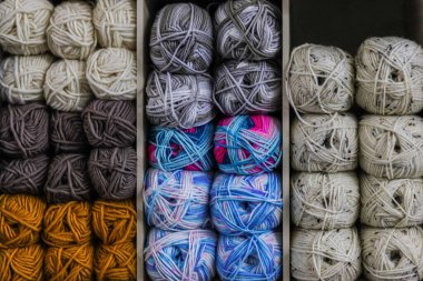 Beyaz arka planda farklı iplikler ve örgü iğneleriyle hasır bir sepet.