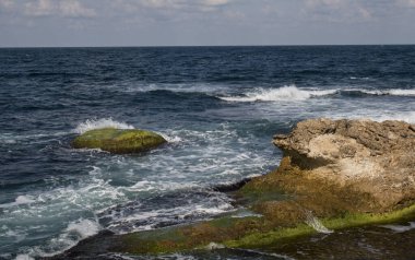 Dalgalar deniz kayalarında sıçrıyor