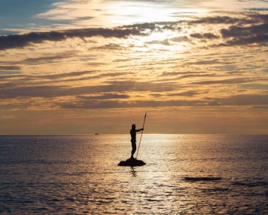 Deniz taşımacılığı, deniz tatilleri. Neptün ya da Poseidon heykeli gün batımında denizde duruyor.