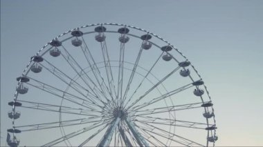 Aile tatili, parkta gezintiler, eğlence gezileri. Gün batımında dönme dolap silueti temiz gökyüzünde. 