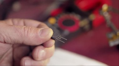 Manual assembly component on circuit board. Preparing the transistor for installation. Close up male hands bend the chip contacts