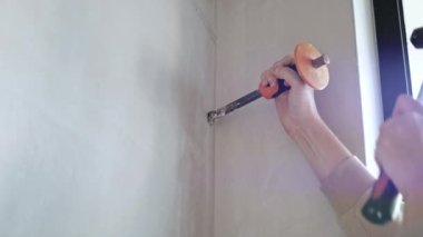 Keskiyi tutan ve çekice vuran elleri kapatın. Klimayı genişleten inşaat işçisi kanalları boşaltıyor.