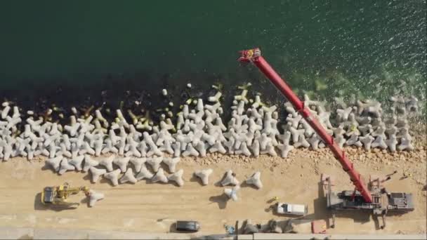 ヘビーデューティクレーンとショベルマシン トップダウンビューによる新しい防波堤の建設の空中ビューのタイムラプス — ストック動画