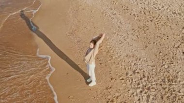 Tatil gezisi ve farkındalık konsepti. Hava manzaralı kadın gün batımında okyanus manzarasına bakıyor huzur ve sükunetin tadını çıkarıyor. Gündelik sonbahar kıyafeti giyiyor.