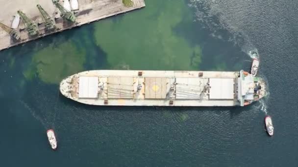 空中自上而下的旋转射击从无人驾驶飞机上起飞 一艘干货谷物船离开了黑海港口 拖曳着帮助 — 图库视频影像