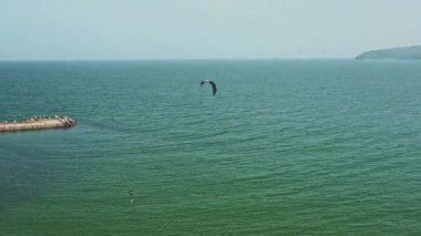 Su sporu, hobi. Okyanus kıyısında uçurtma sörfü yapan bir insan, insansız hava aracından gelen rüzgarı yakalar.