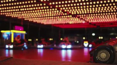 Lunaparkta aile eğlencesi. Tanımlanamayan çocuklar gece çarpışan arabaları sürüyorlar, park halindeki arabalara odaklanıyorlar.