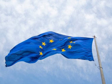 Avrupa Birliği bayrağı Avrupa Parlamentosu binasının önünde dalgalanıyor. Brüksel, Belçika, güneşli mavi gökyüzü