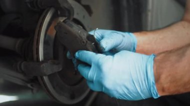 Araç bakımı. Tamirci tamirhanede araba frenleri üzerinde çalışıyor. Yakından erkek eli montajdan önce eski ve yeni pedleri karşılaştırır. Eldiven tak.