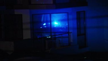 Suç mahalli. Geceleri acil durum mavi ışıkları yanıp sönüyor. Evin pencerelerinde yansıma var.