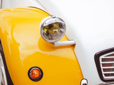 Farları yakın planda olan klasik bir retro araba. Sahilde park edilmiş sıcak bir araba.