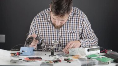 Mühendislik yeteneği olan bir adam lehimleme demiriyle radyo parçaları üzerinde çalışıyor..