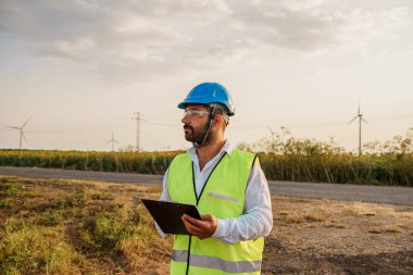 Erkek mühendis rüzgar türbini çiftliği enerji üretimini kontrol ediyor. Rüzgar türbini mühendisi çalışıyor