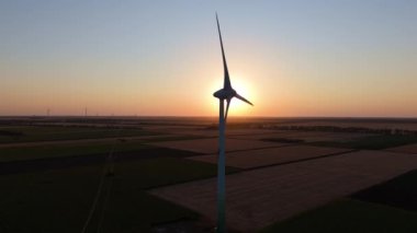 Sıfır emisyon yenilenebilir enerji. Rüzgar türbini silueti batan güneşin önünde sürdürülebilir enerji sağlıyor