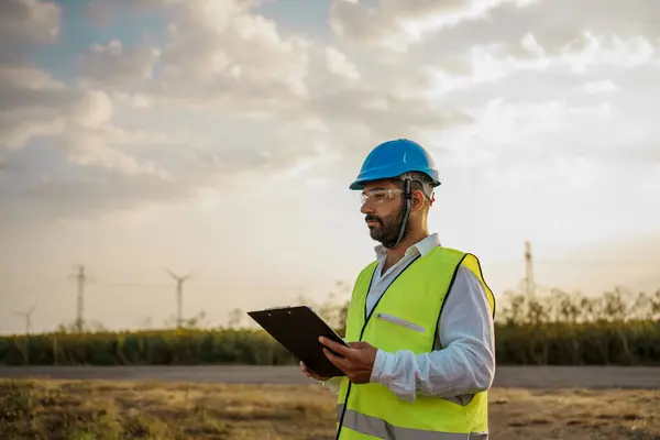 stock image Maintenance engineer checks the checklist for a defective turbine in a wind turbine park. Portrait of skilled professional. European green deal