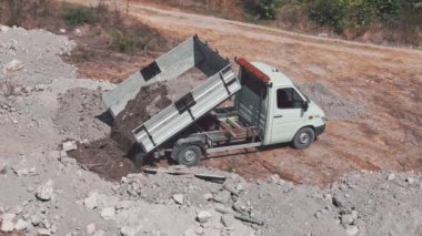Küçük bir çöp kamyonu yeni bir inşaat alanından toprağı kaldırıyor. Bir çukur kazmak, inşaat alanından atık çıkarmak.
