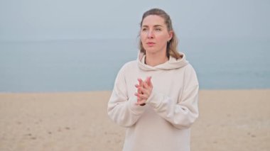 Deniz kıyısında spordan önce ellerini ısıtan genç bir kadının portresi. Sahilde ısınma, sağIık..