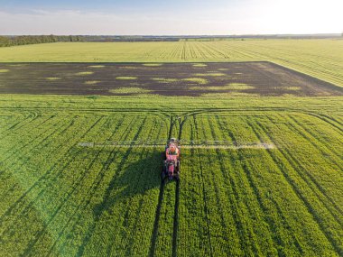 Lush Green Field 'da modern traktör ilaçlama ürünleri. Hava ön görünümü.