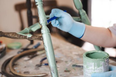 Eldivenle kadın elini kapat eski bir tahta sandalyeyi restore et, sandalyeyi boya. Garajda küçük bir işletme