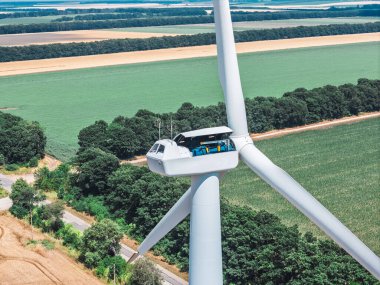 Teknisyen yüksek irtifada rüzgar türbini bakımı yapıyor. Havadan