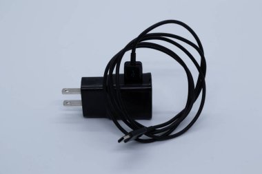 Beyaz arkaplanda siyah şarj aleti ve kablo