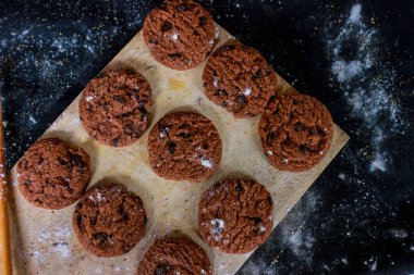 Tahta kesme tahtasında servis edilen çikolatalı bisküviler. Besleyici atıştırmalık, tatlı ya da kahvaltı. Siyah arka plan. Yiyeceğe yakın çekim. Kuru üzümlü kek..