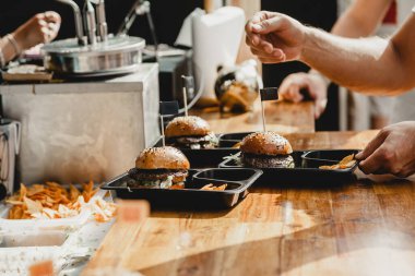 Hamburger şöleninde elinde hamburgerler tutan bir adam. Hamburger Yemek Şöleni Partisi. Açık hava sokak yemekleri festivalinde büyük burger ellerde. Festival yemeği günü.