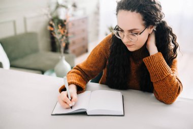 Defterde yazan kadın. İş kadını ya da genç bayan öğrenci elinde kalemle kağıt defter günlüğüne yazıyor, notlar alıyor çalışıyor, ödev yapıyor, kontrol listesi yapıyor. Görüntüyü kapat.