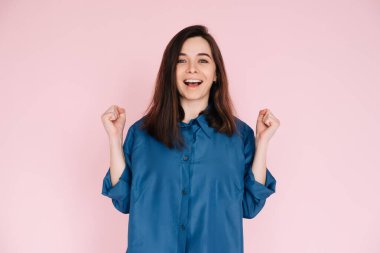 Zaferi Kutlayan Öforik Kadın, Zafer Yumrukları: İzole Pembe Arkaplan Portresi. Coşkulu Kadın Başarı Kutlaması, Heyecanlı Yumruklar: Ayrı Pembe Arkaplan Portresi.