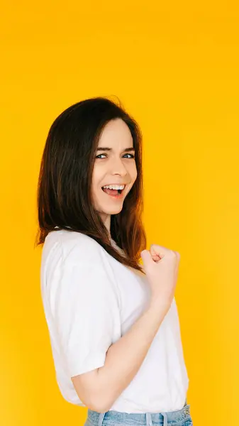 stock image Victory Gesture: Enthusiastic Lady with Fist Raised in Triumph, Shouting in Excitement - Capturing Success, Achievement and Positive Energy Against a Yellow Background.