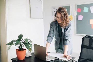 Modern Ofis 'te dizüstü bilgisayarla uğraşan genç profesyonel bir kadın. Öğrenci Kız İş Dünyasında Serbest Çalışmayı Kucaklıyor. Canlı Yaşam Tarzı Konsepti