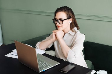 Connected and Smiling. Woman with Wireless Headphones Engages in Laptop Video Call, Watching and Talking. Happy Woman with Wireless Headphones Engages in Laptop Video Call. clipart