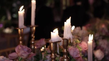 Mumlar ve çiçeklerle dolu bir masa. Sahne romantik ve samimi.