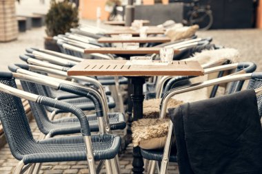 Avrupa 'da bir kentte kaldırım taşı caddesinde boş masaları ve dokuma sandalyeleri olan büyüleyici bir kafeterya. Seyahat, konukseverlik ve yaşam tarzı için mükemmel bir ortam.