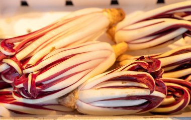 Bir çiftçi pazarında ince kırmızı ve beyaz yapraklı taze Treviso radicchio. Yemek fotoğrafçılığı, taze tarım ürünleri, gurme yemekleri ve sağlıklı beslenme kavramları için idealdir.