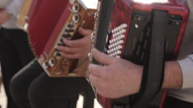 Açık havada akordeon çalan iki müzisyen, ellerinin ve enstrümanlarının yakın görüntüsüne sahipler. Müzik kültürü, sokak eğlencesi ve halk gelenekleri için harika..