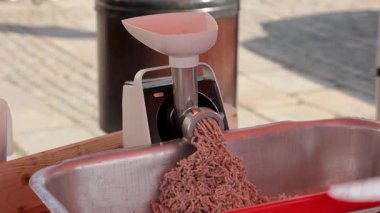 Açık pazarda elektrikli öğütücü kullanarak çiğ eti elle öğüten bir adam. Yiyeceklerle ilgili görseller, kasap temalı içerik ya da aşçılık sektörü promosyonu için mükemmel.